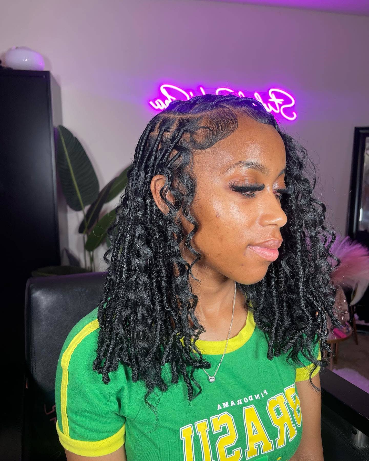 Invisible locs styled in a messy bob with loose curls and a side part.