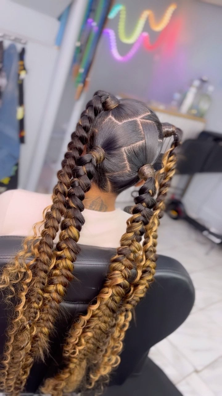 Person with four butterfly braids, featuring added extensions for length and a wavy texture at the ends.