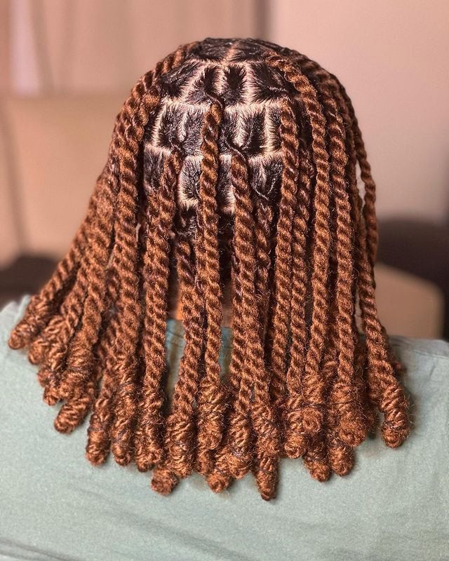 Shoulder-length invisible locs in a rich copper color, arranged in a structured and defined pattern.