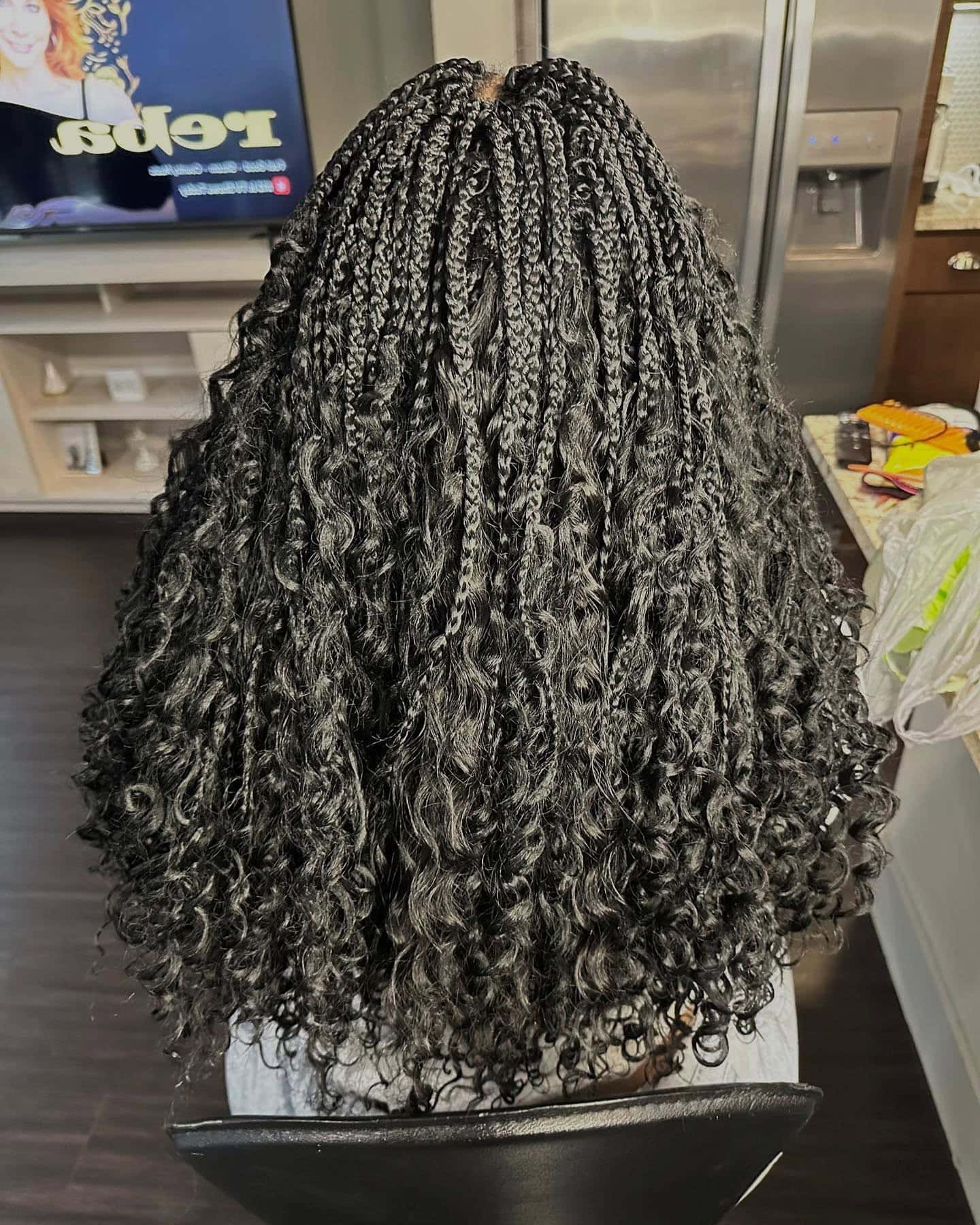 Back view of a person with voluminous crochet braids, displaying the combination of natural curls and added braids.