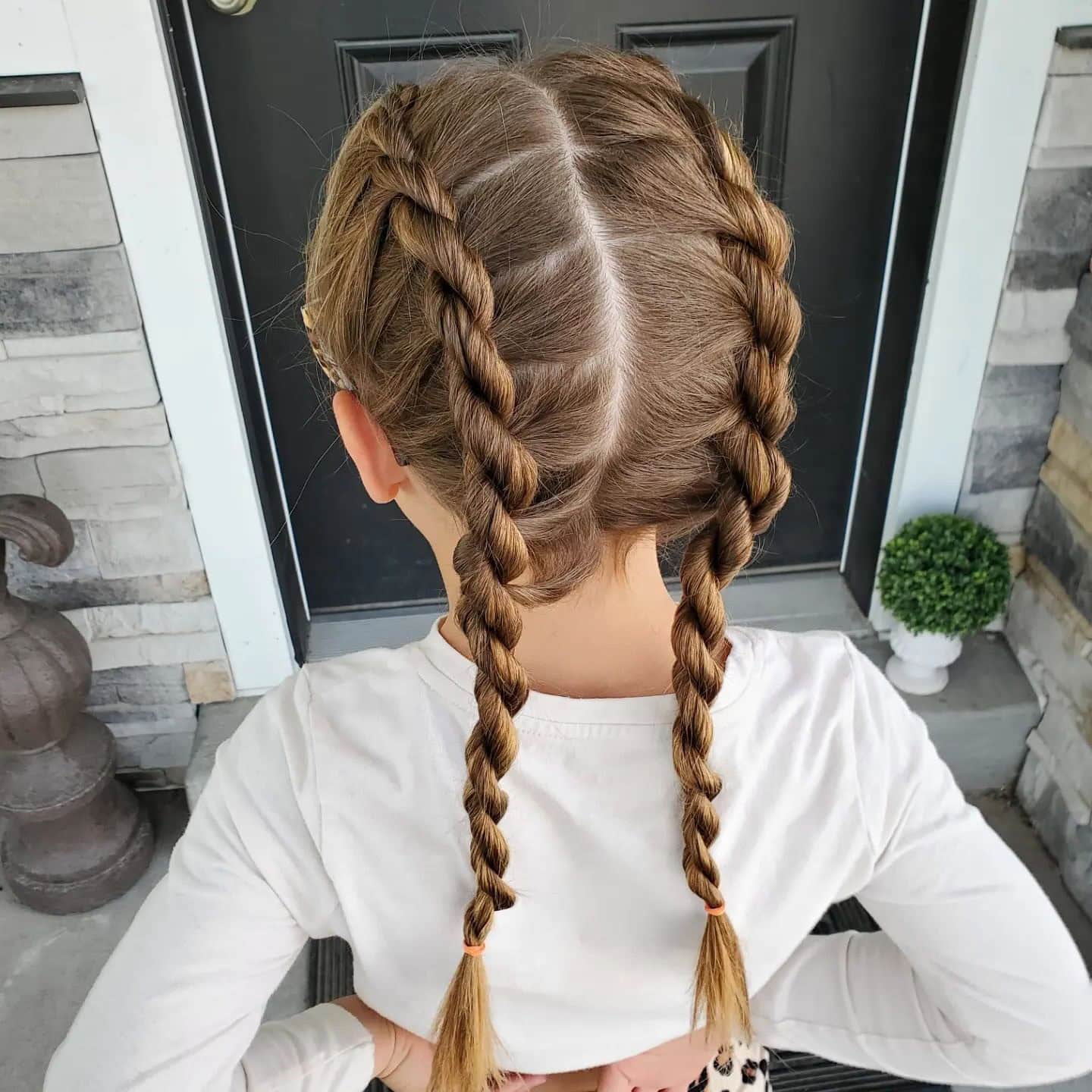 A young girl with two rope braids starting from the crown and ending at the nape.