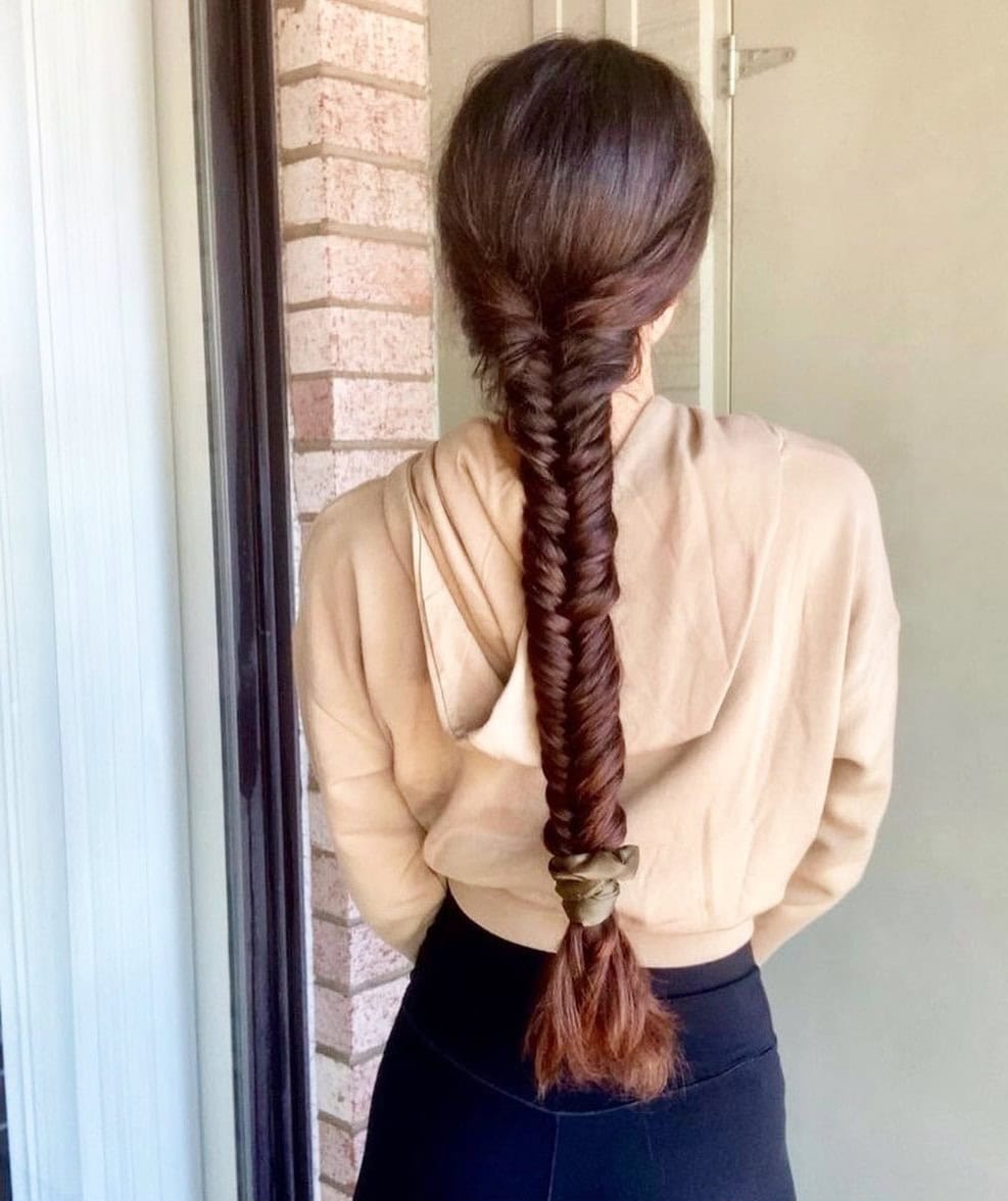 A woman with a long fishtail braid extending from the nape of her neck down her back.