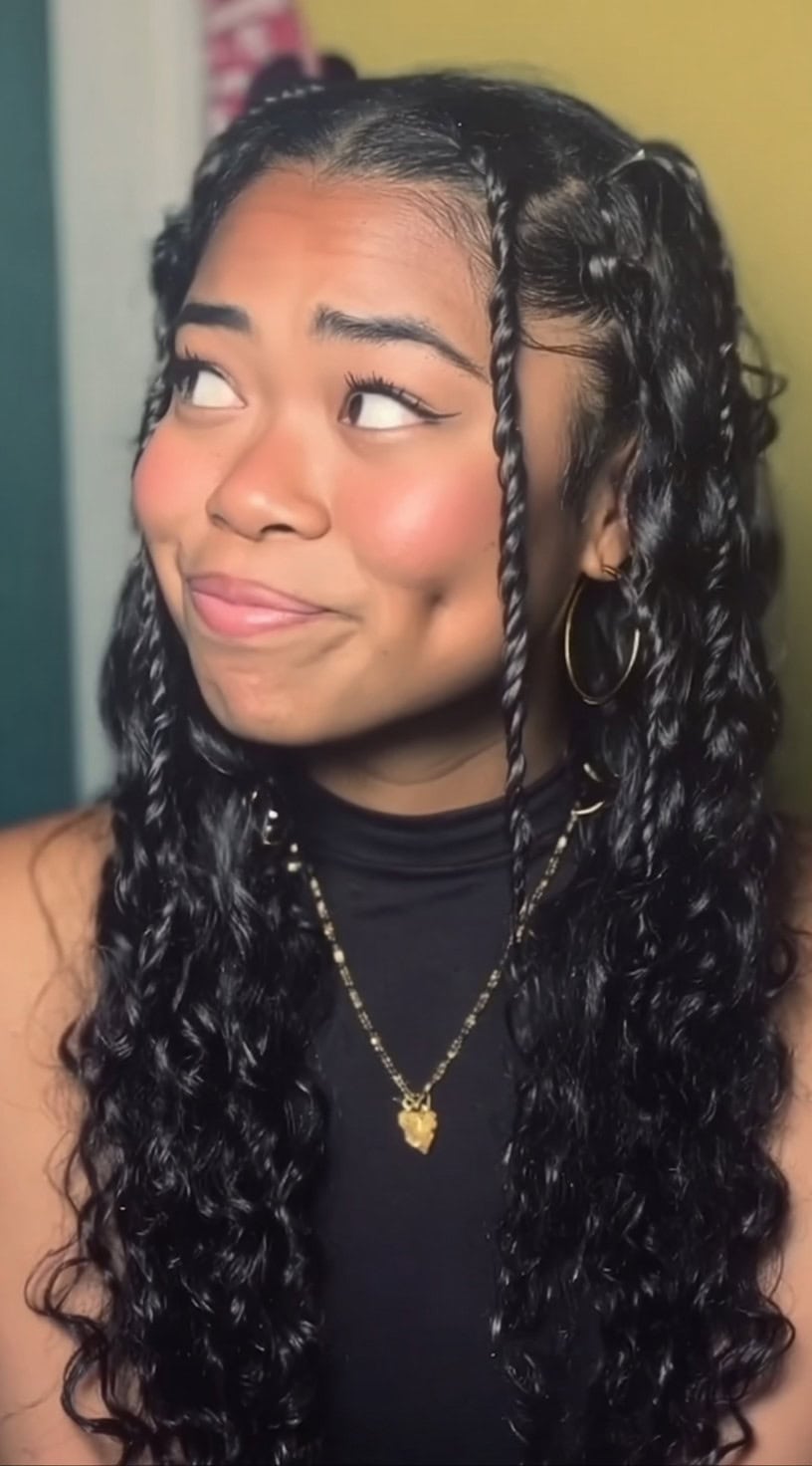 Young woman with long 3a curls wearing small front twists while the rest of her curls hang freely.