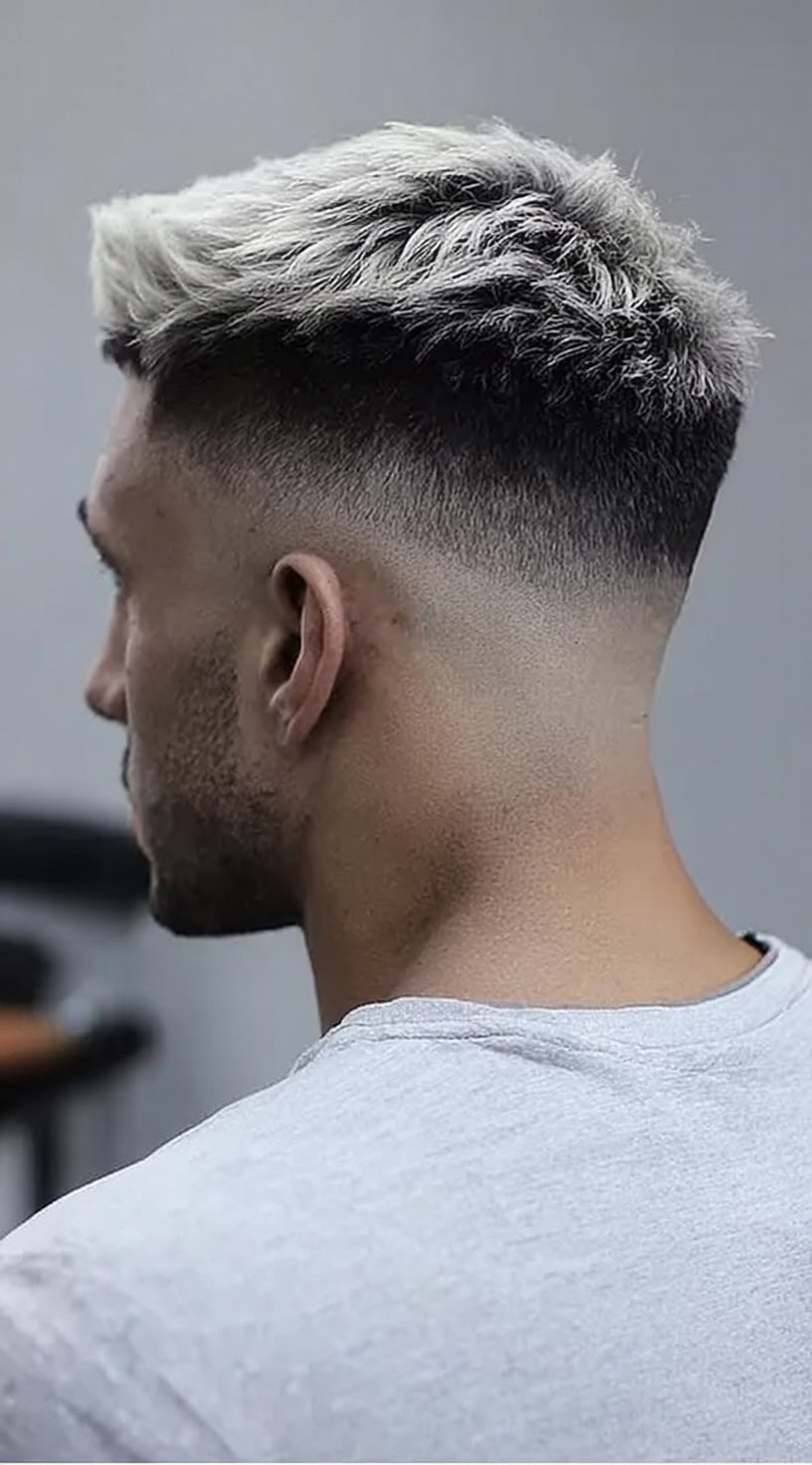 Man with a high skin fade and short textured white hair on top.