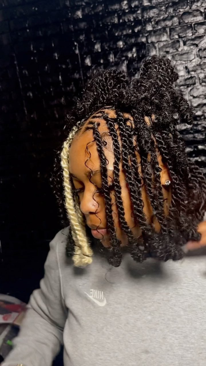 Invisible locs styled in a bob with a blonde peekaboo highlight and curls.