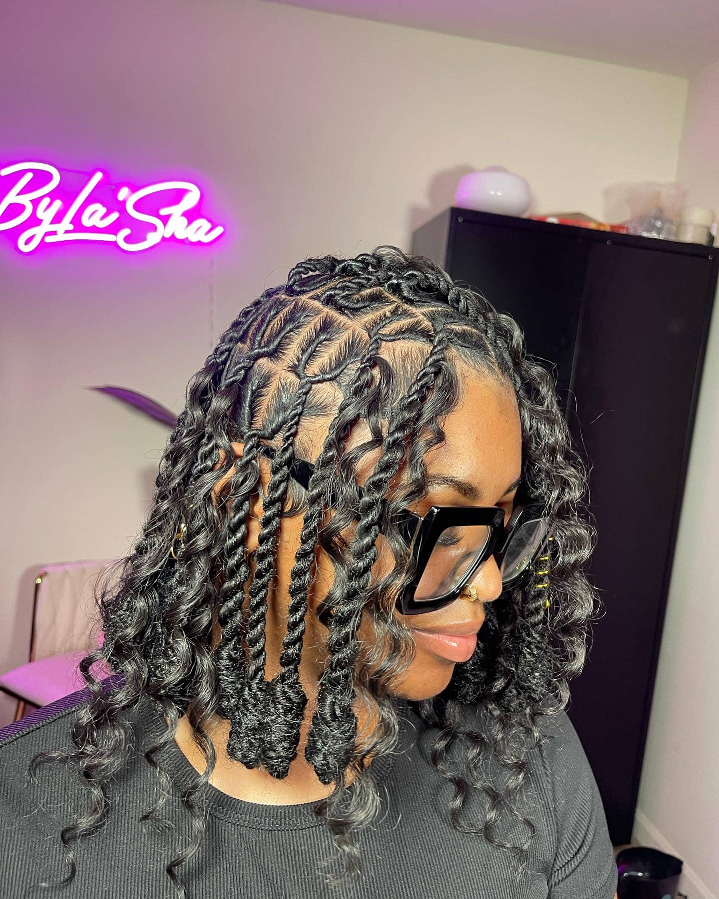 Invisible locs styled in a bob with defined curls for a voluminous look.