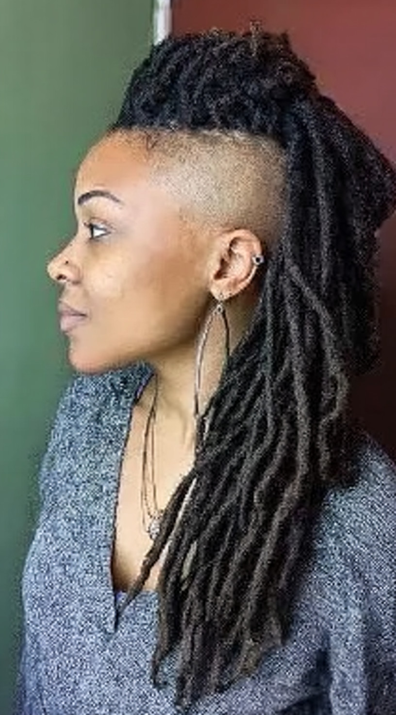 Side profile of a woman with long locs styled into a mohawk, paired with shaved sides.