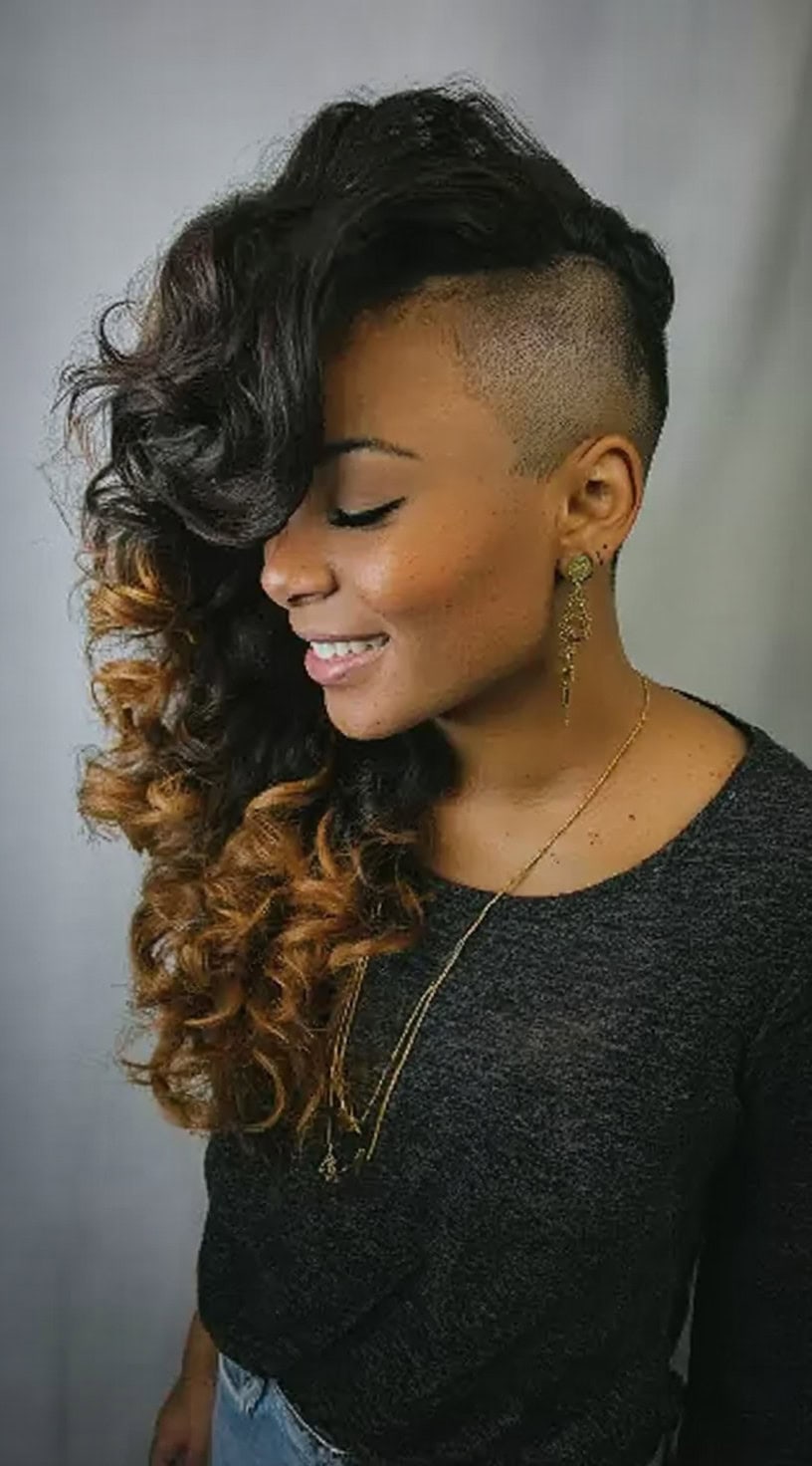 Smiling woman with long ombre curls and a deep, closely shaved undercut on one side.