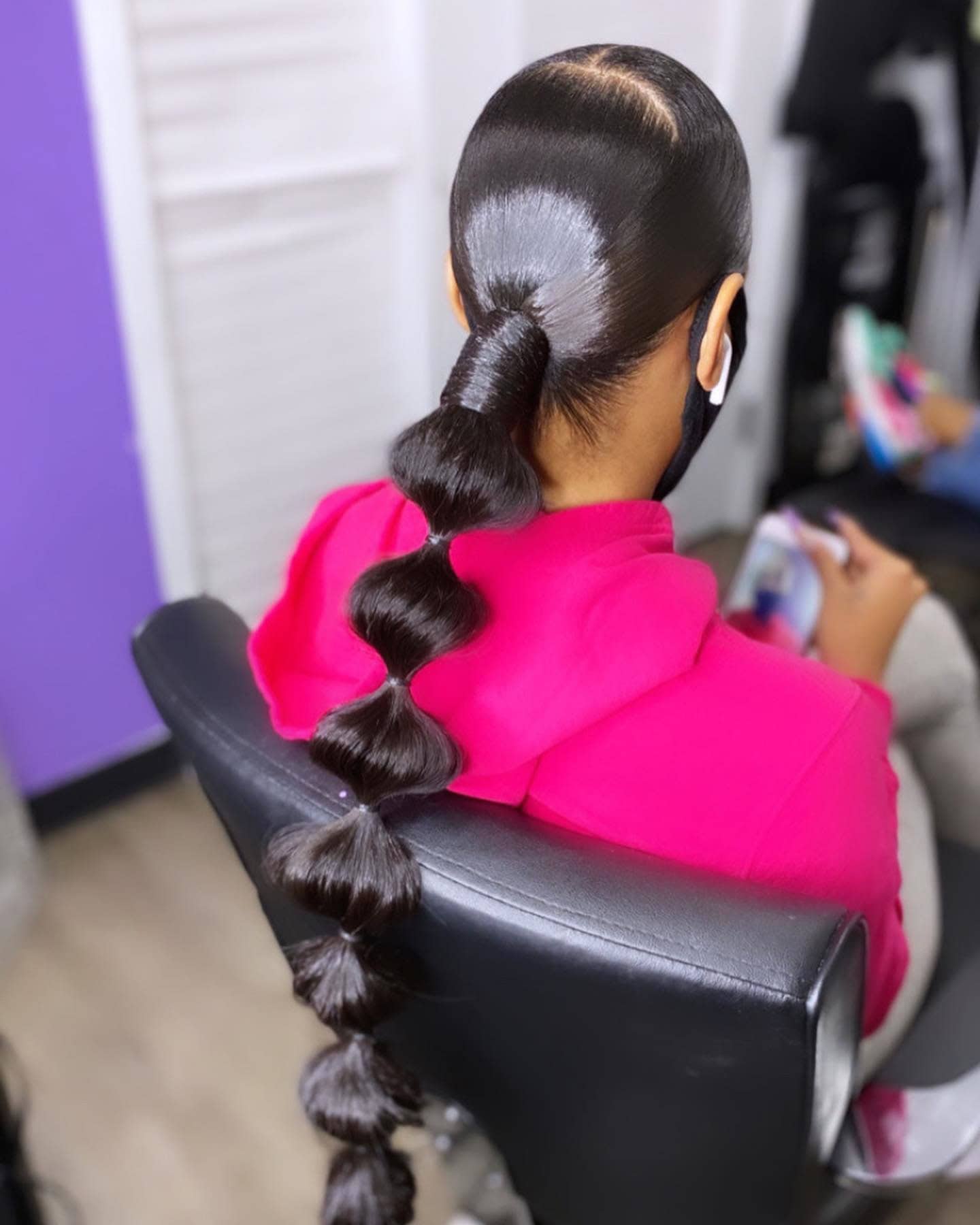 Back view of a person with a low bubble ponytail, showcasing a sleek and smooth look with evenly spaced hair ties creating 'bubbles'.