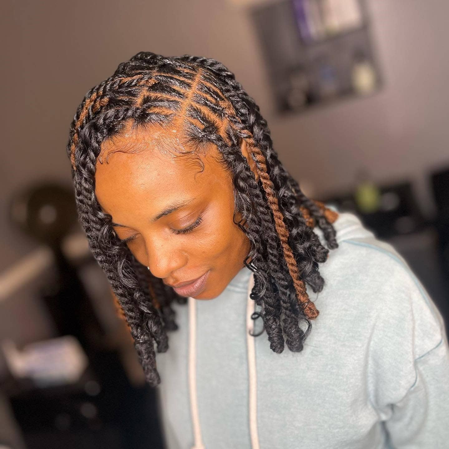 Short invisible locs with curls and subtle highlights, styled to frame the face.