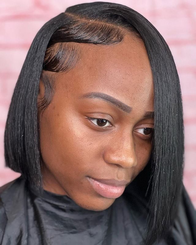 This photo shows a woman with a sleek bob haircut and sharp side part, with bangs covering one eye.