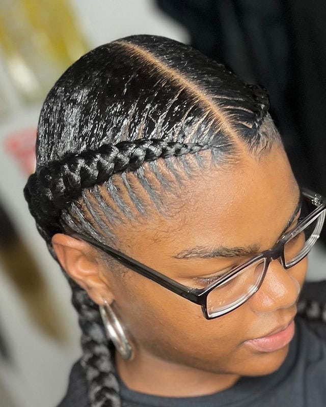 Close-up of a person with sleek Dutch braids, parting in the middle and neatly braided down the sides.