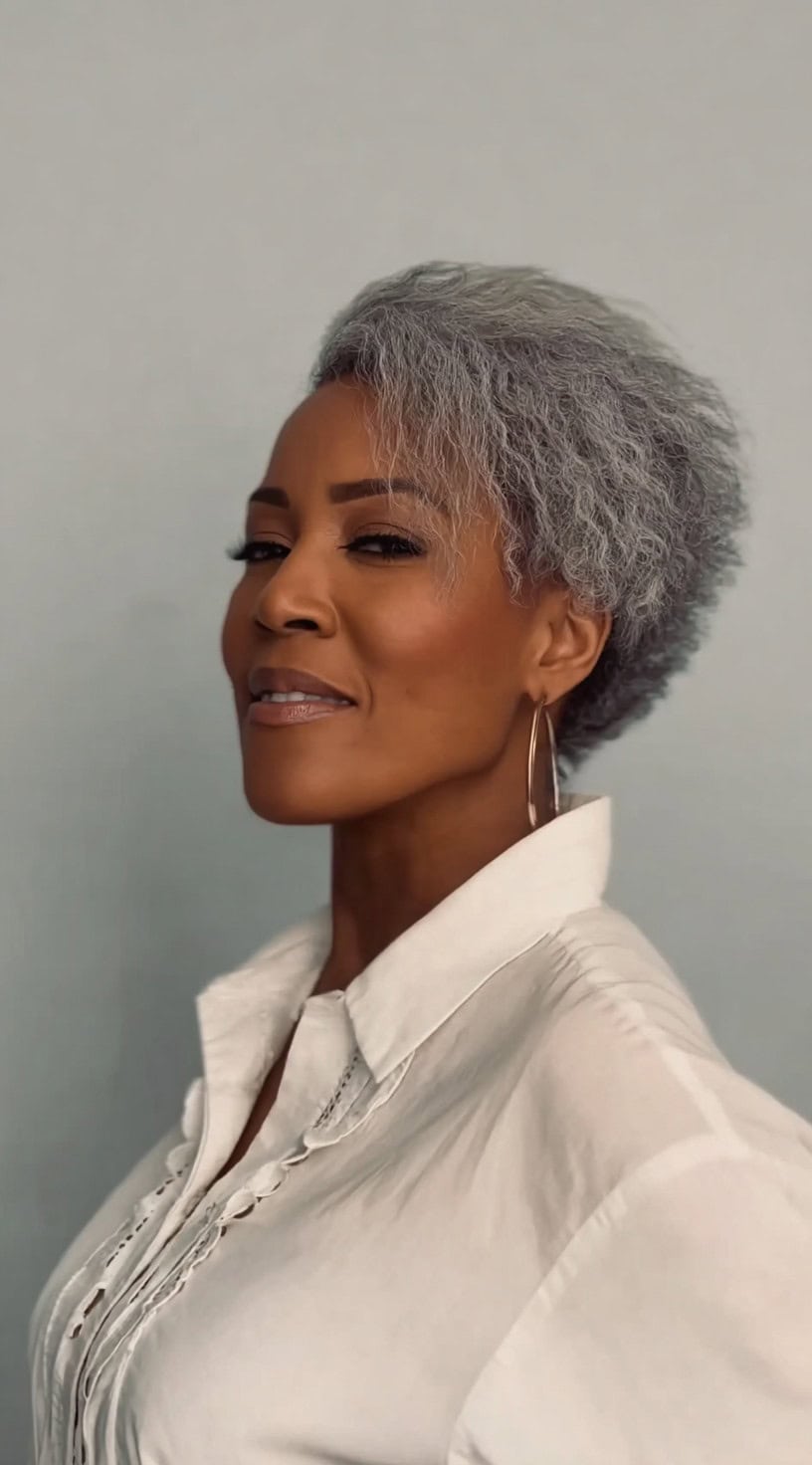 Side view of a woman with a short tapered cut and natural salt and pepper afro-textured hair.
