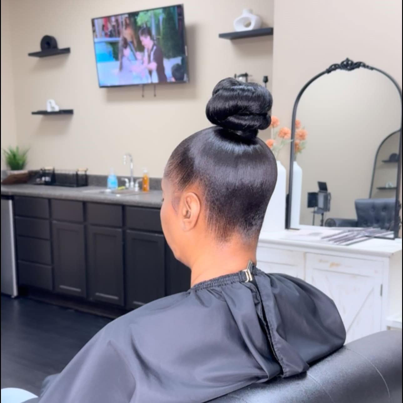 Back view of a person with a sleek top knot, showcasing a smooth, polished bun.