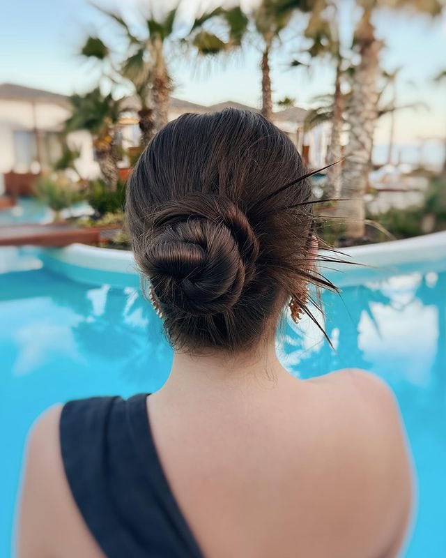 A woman with dark hair styled into a low, twisted bun at the nape of her neck.