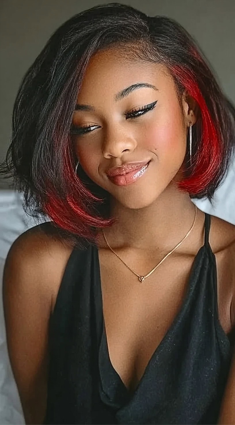 Young woman with a voluminous side-swept bob revealing a bright red peekaboo underlayer.