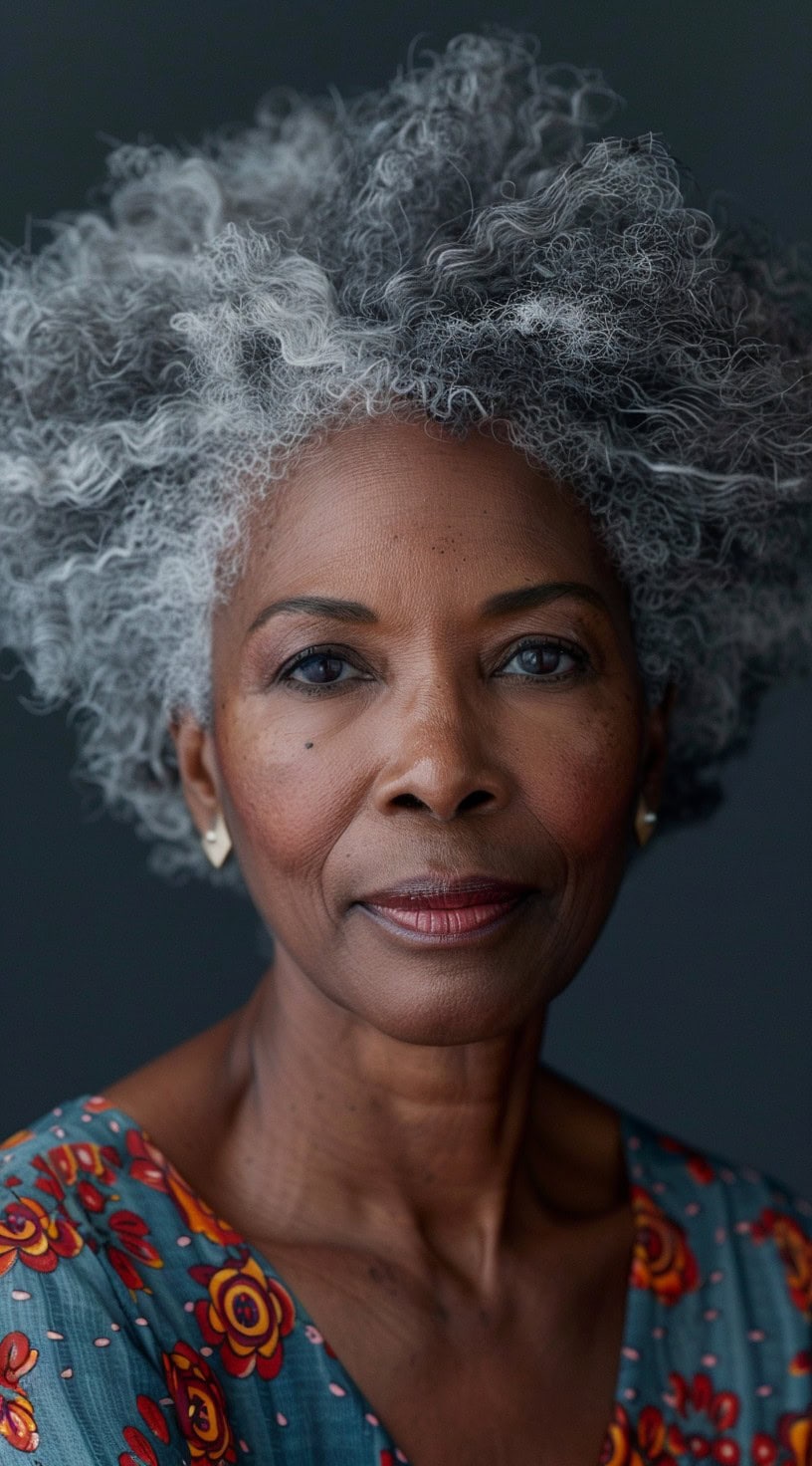 In this photo, a woman with voluminous silver curls is shown against a dark background.