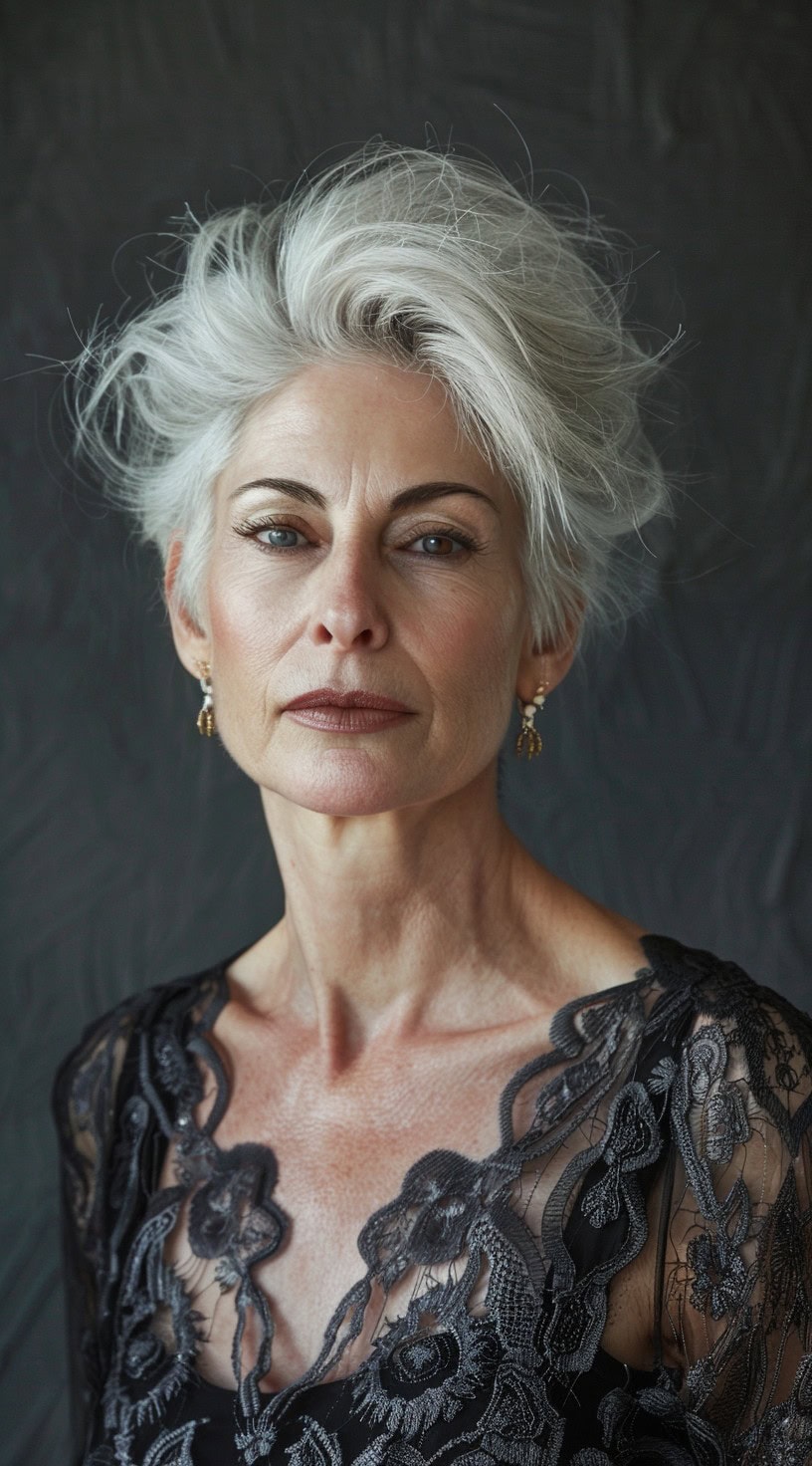 In this photo, a woman with voluminous silver hair and a textured top gazes confidently.