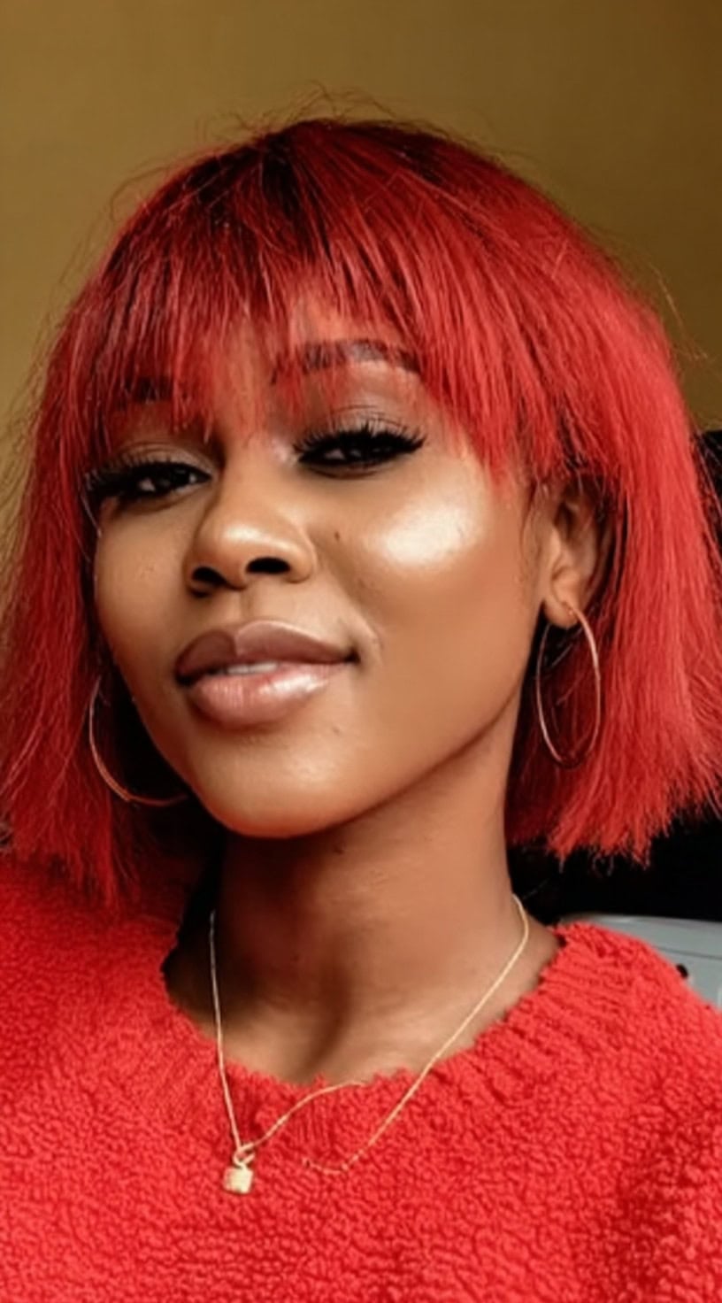 A blunt red bob with a straight-across fringe and textured ends creating a bold, graphic shape.