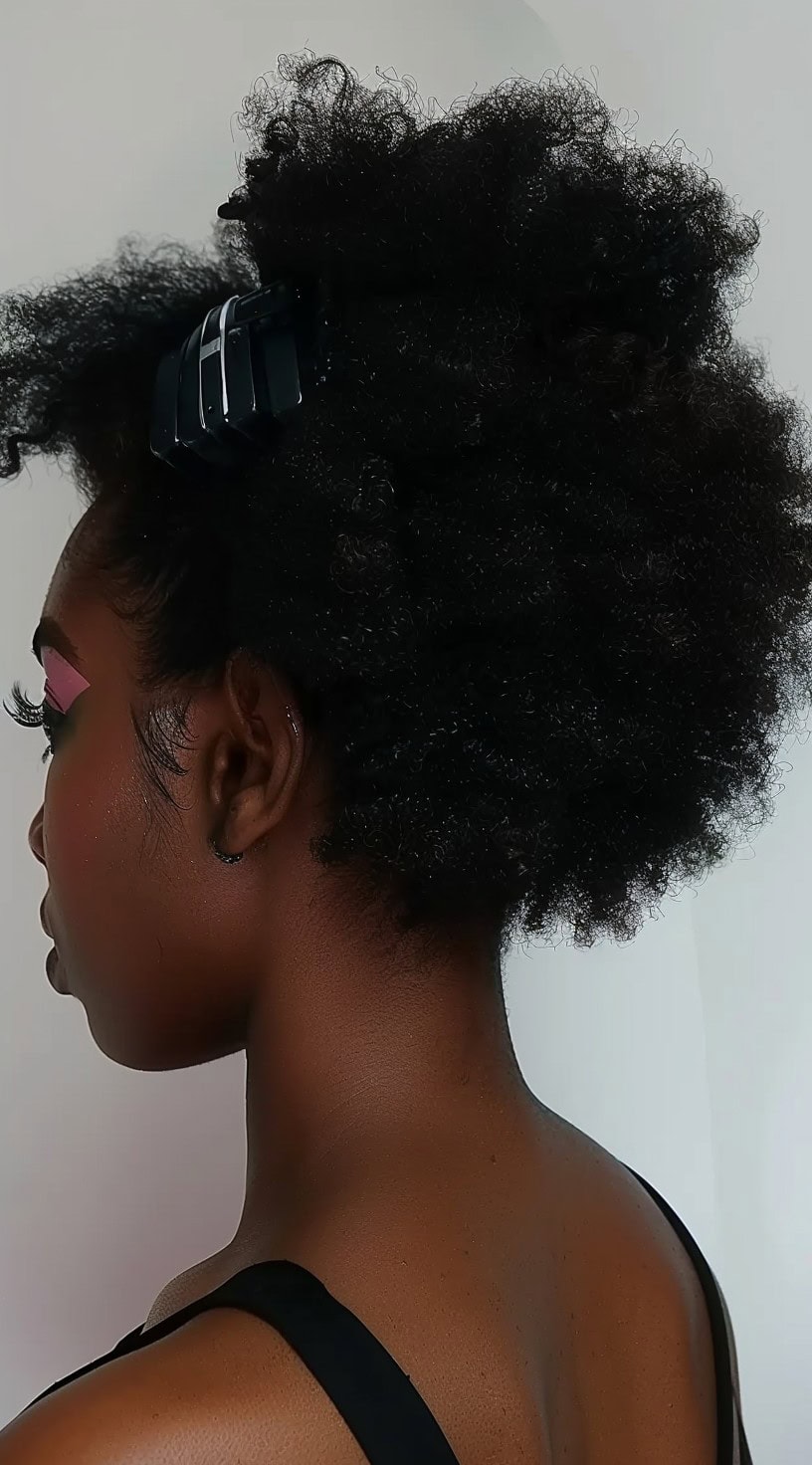 An image of a woman with 4c hair styled into a claw clip updo.