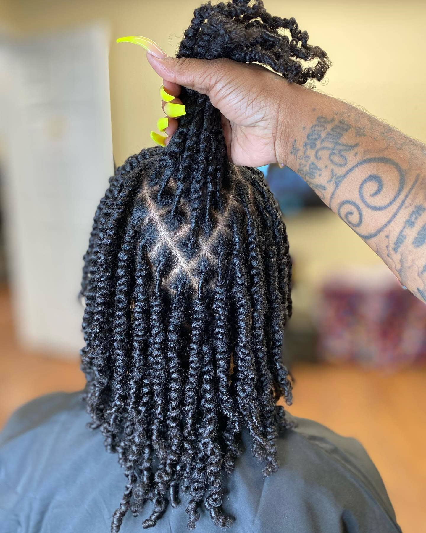 A person holding up their hair to reveal diamond-shaped partings with two-strand twists.