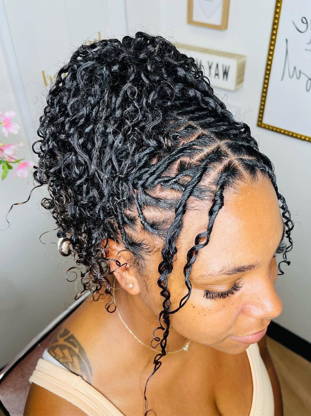 A person with two-strand twist locs styled in a high updo with tendrils framing the face.