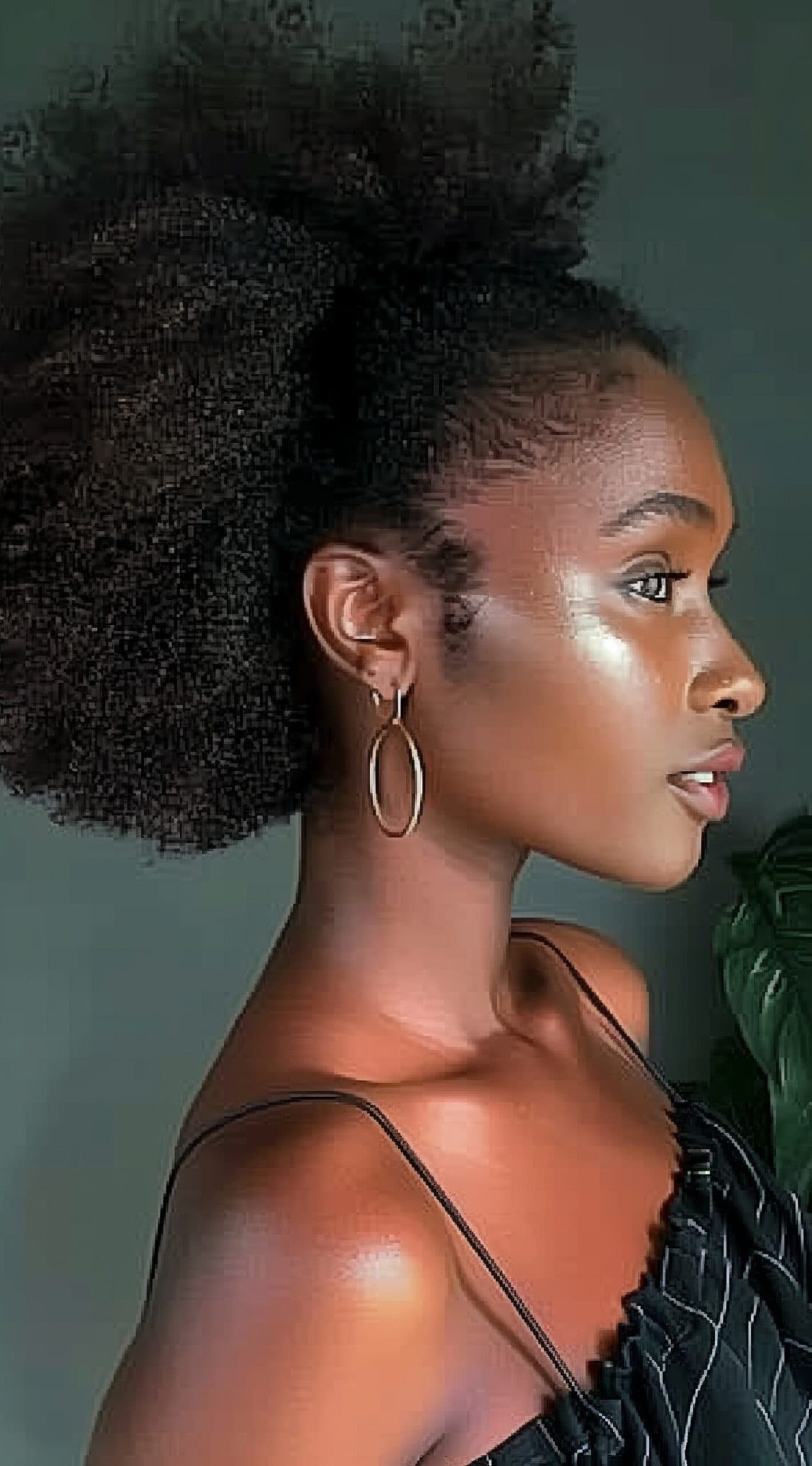 A woman with a low afro puff ponytail in a side profile view.