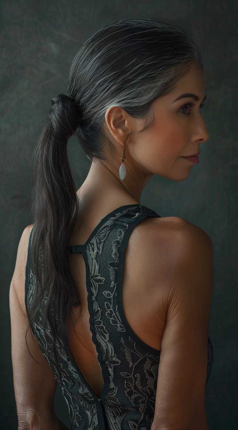 Low ponytail hairstyle on a woman with sleek, dark hair, secured at the nape of the neck.