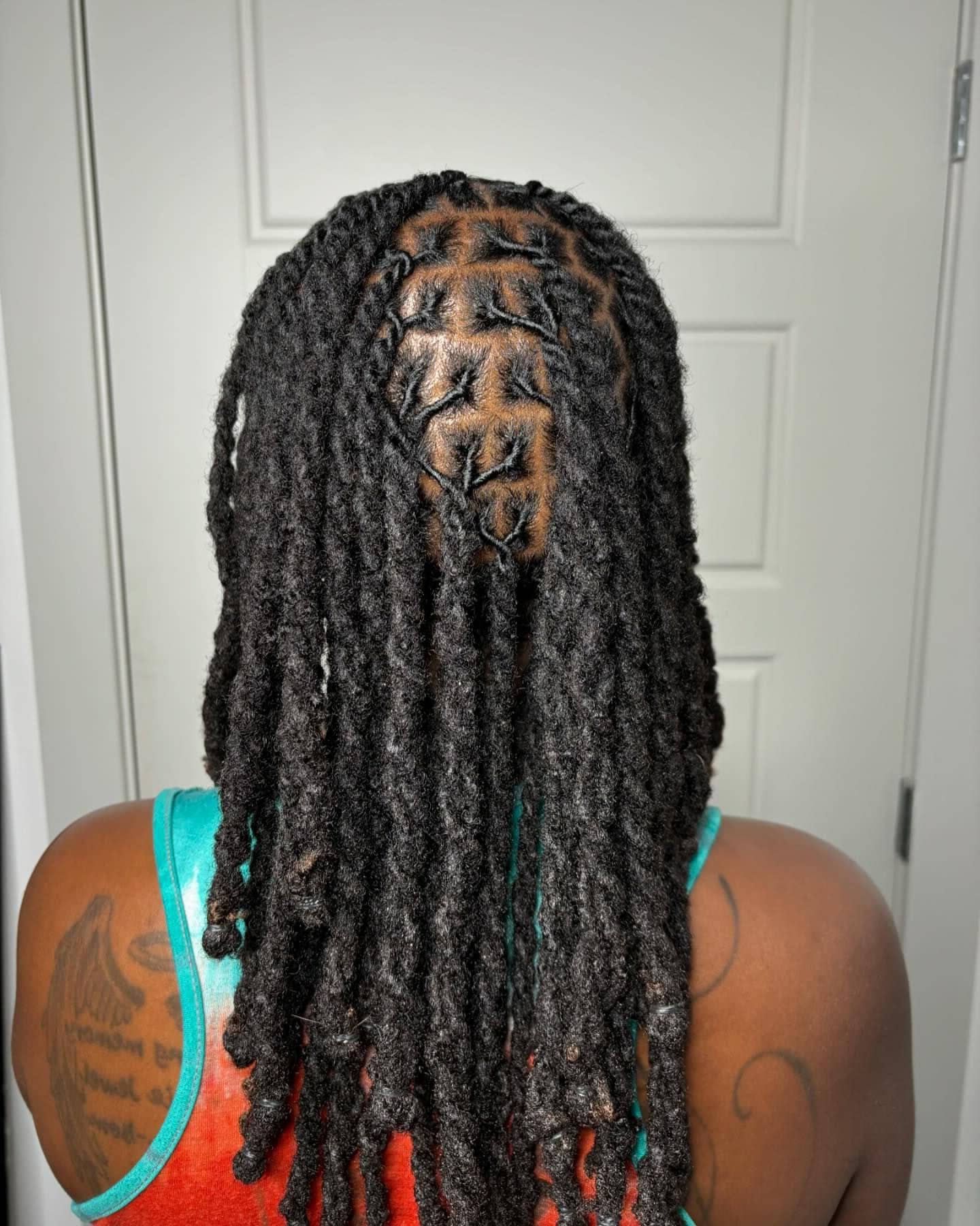 A person with medium to long two-strand twist locs styled in layers.