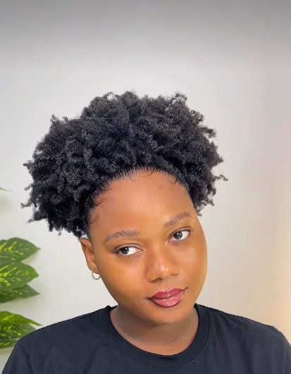 A woman facing the camera with a rounded 4c puff pulled back smoothly, creating a soft halo effect.