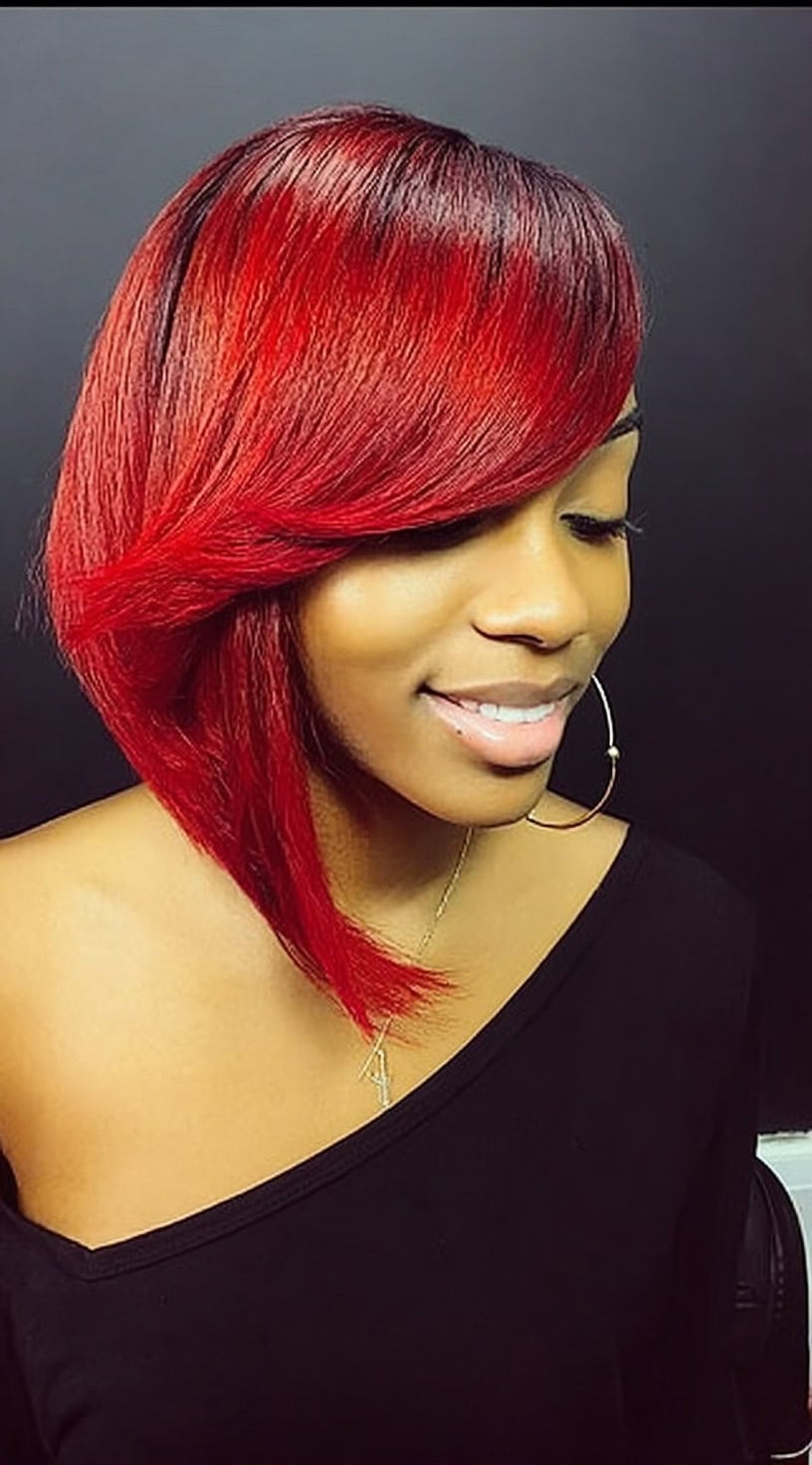 A sleek ruby red asymmetrical bob with a deep side part and longer front section.