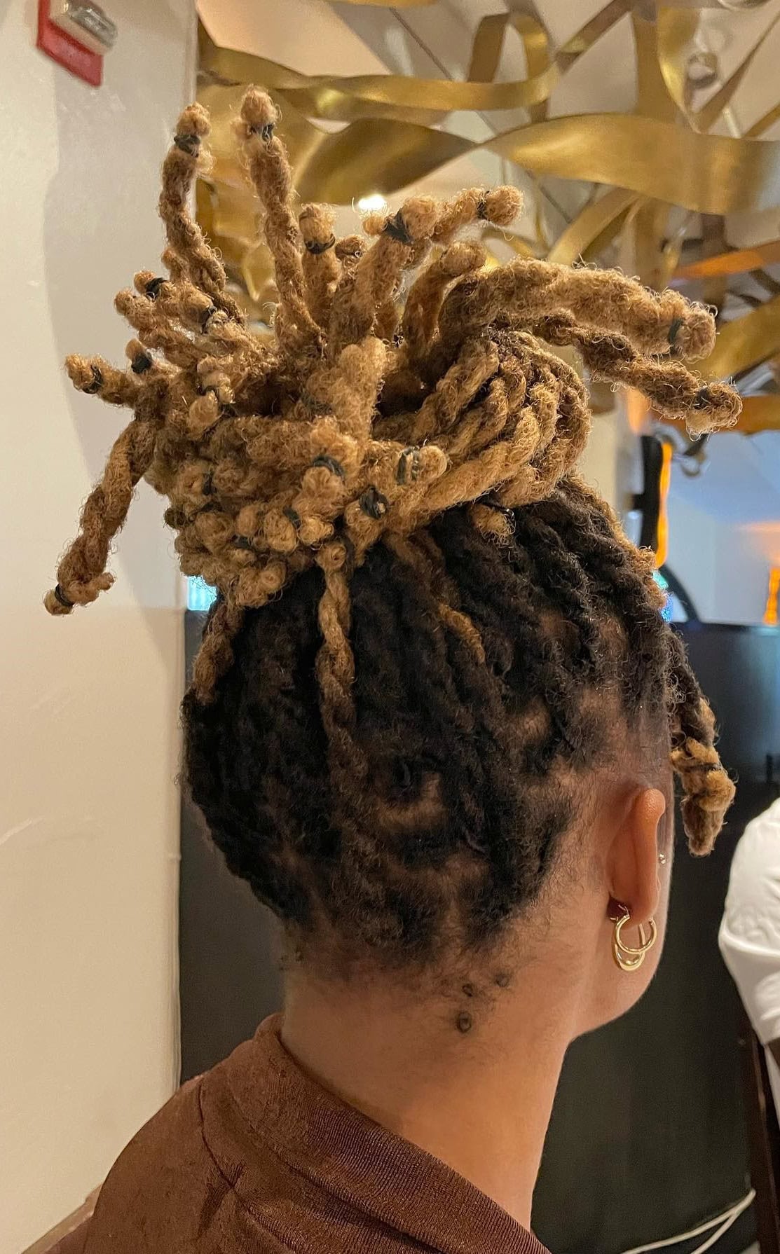 A woman with two-strand twist locs styled in a pineapple updo with twist bangs.