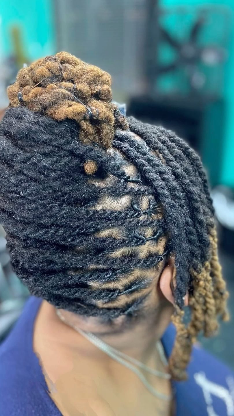 A person with two-strand twist locs styled in an updo with side-swept bangs.