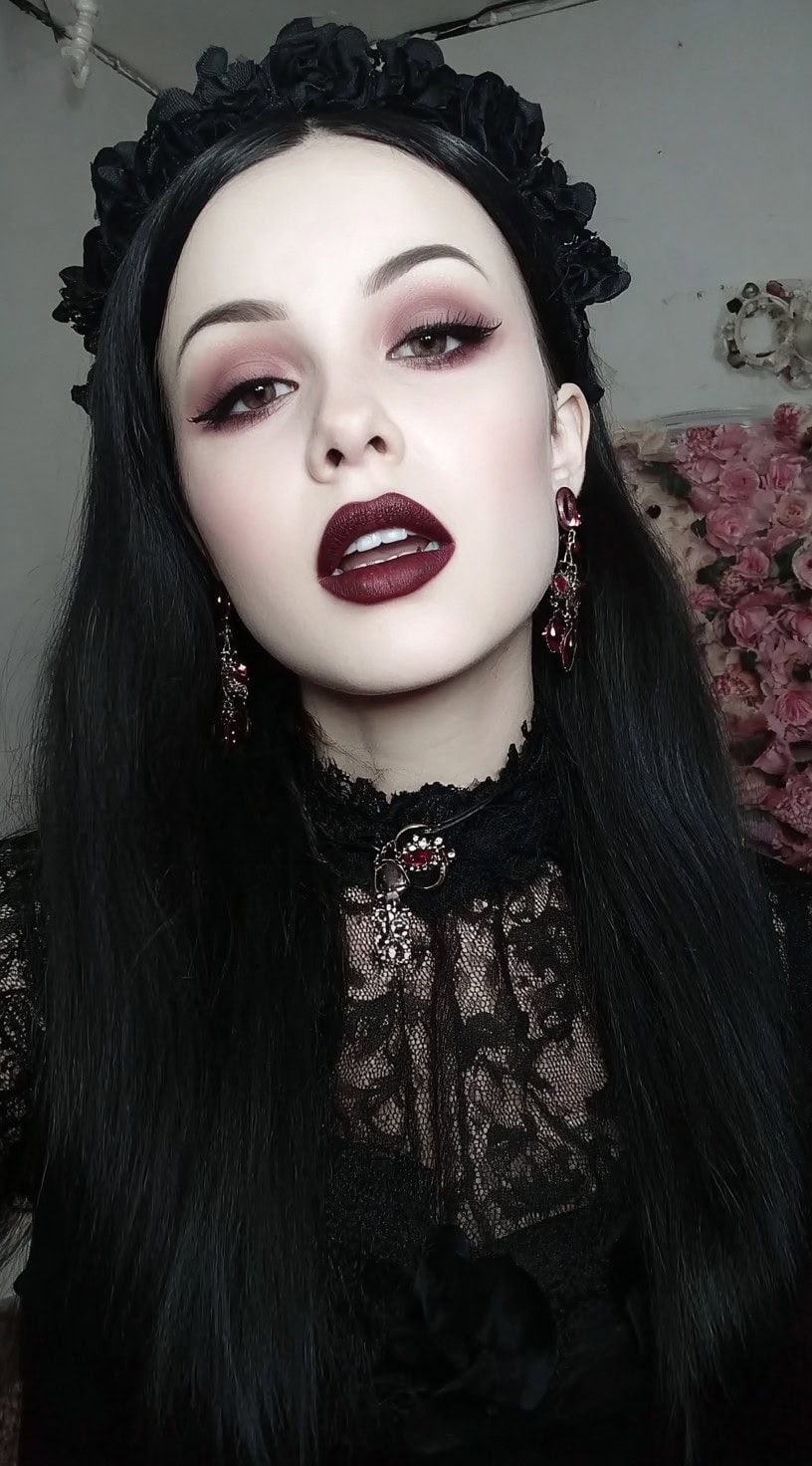 Straight jet-black hair adorned with a black rose crown, paired with dark makeup.