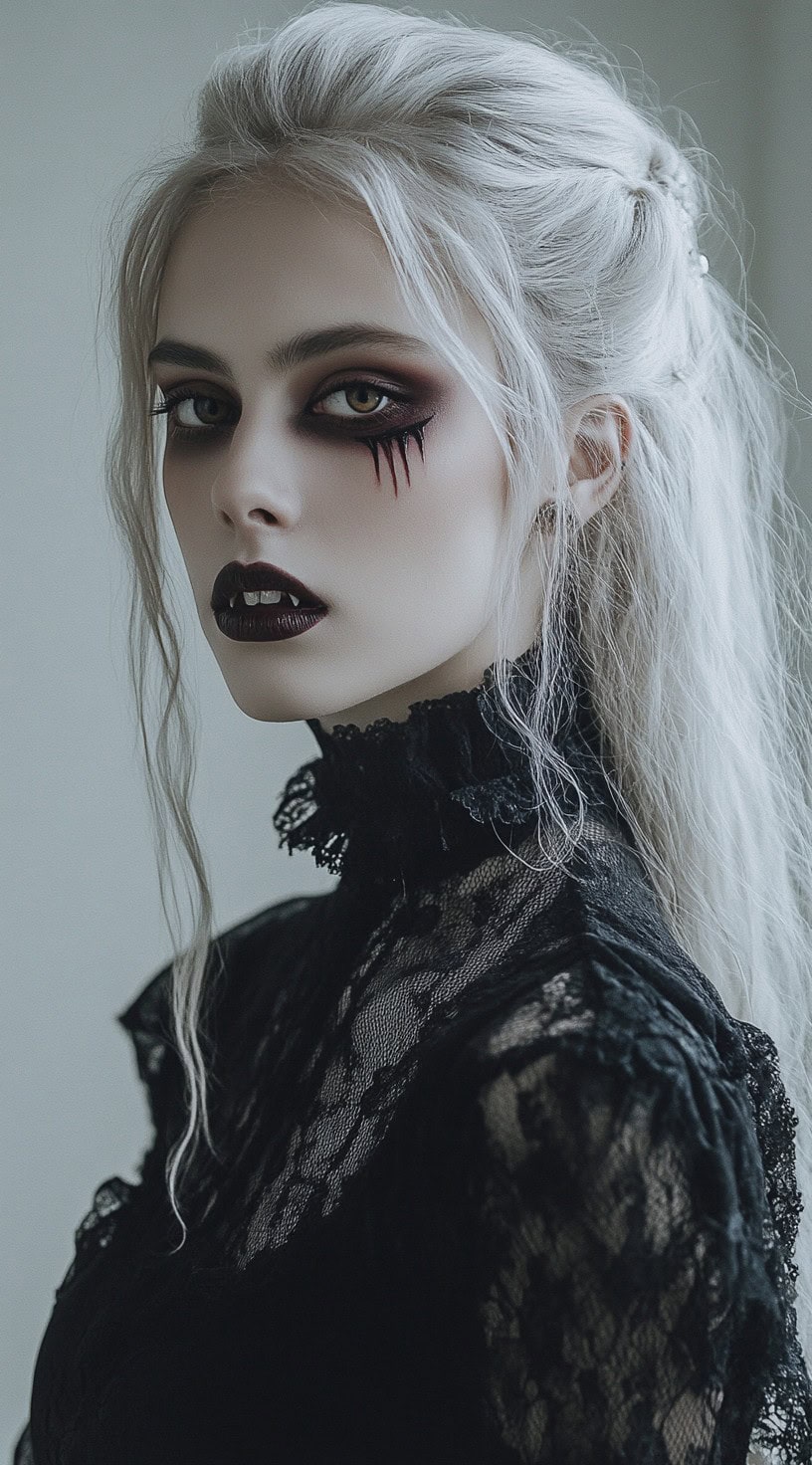 Side view of a woman with a half-up, half-down hairstyle with loose tendrils framing her face and vampire makeup.