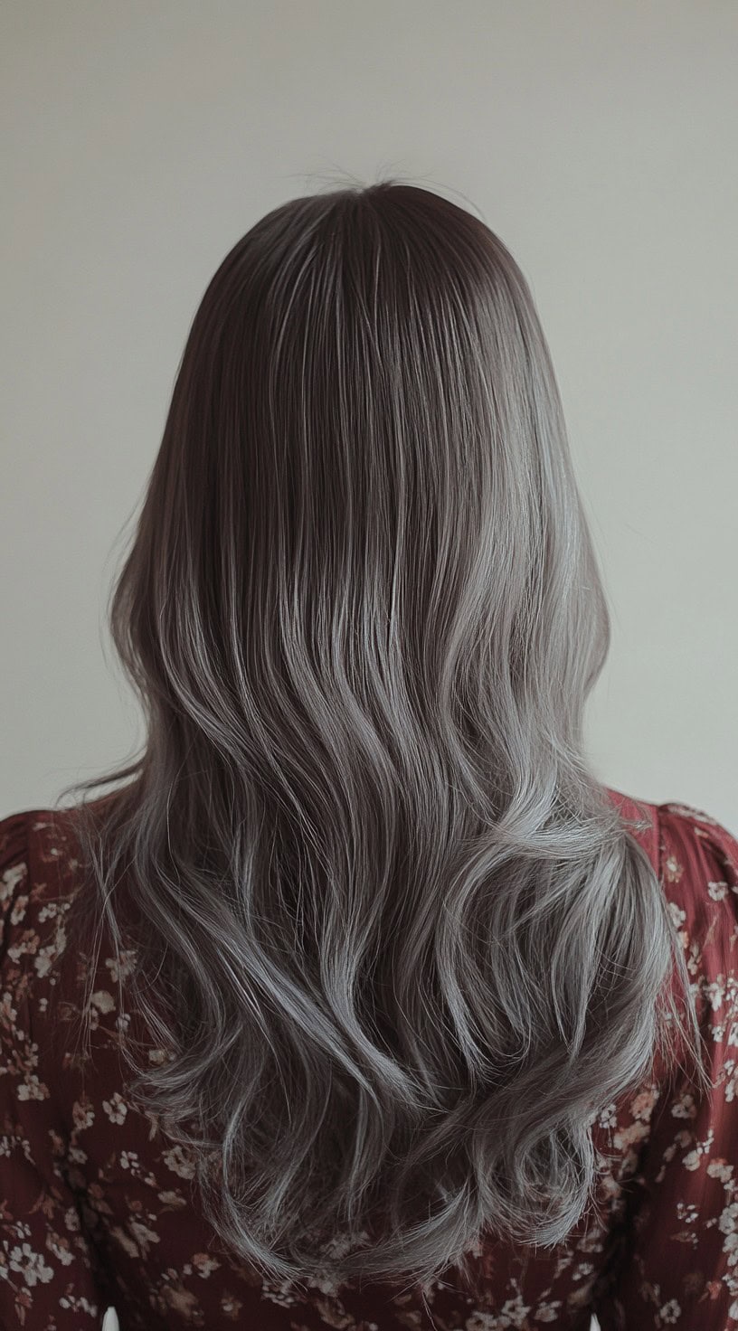 A back view of long, wavy brown hair with a soft silver sheen highlighting the flow of the waves.