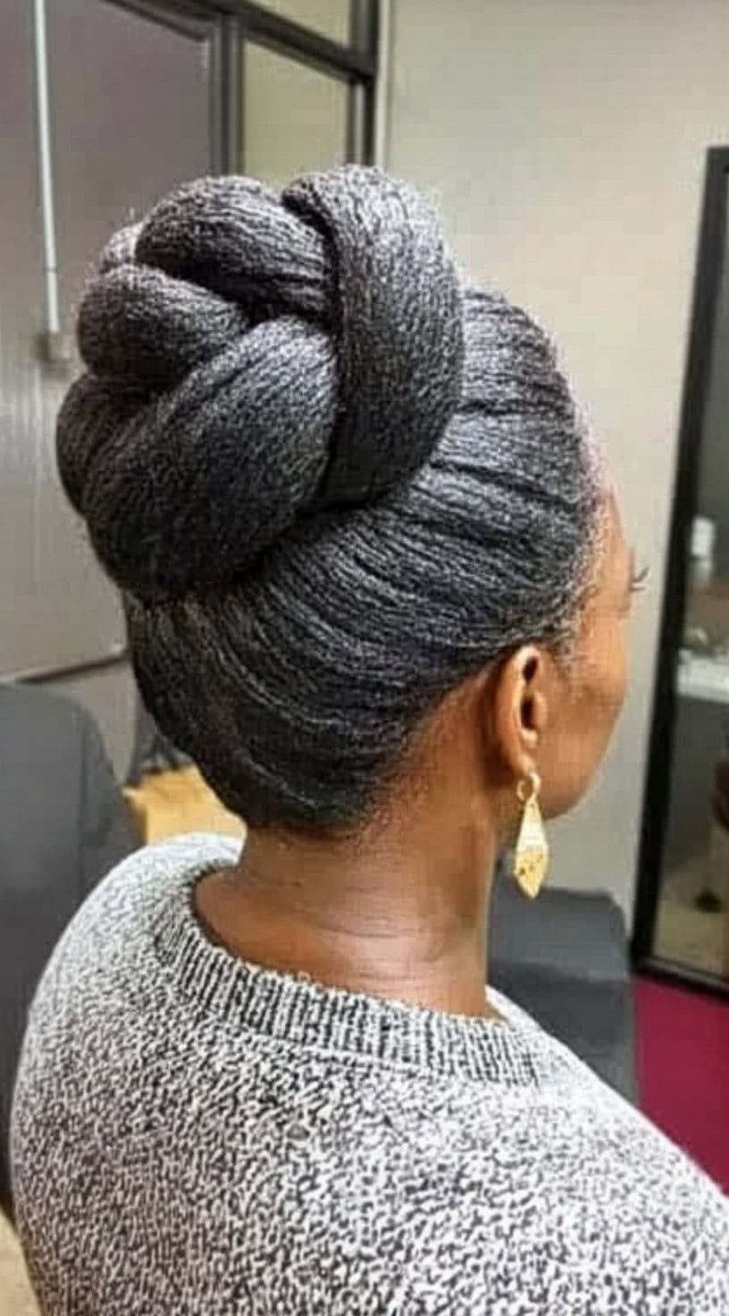 Rear view of a woman wearing an elegant, high twisted bun showcasing smooth, silver-gray hair.