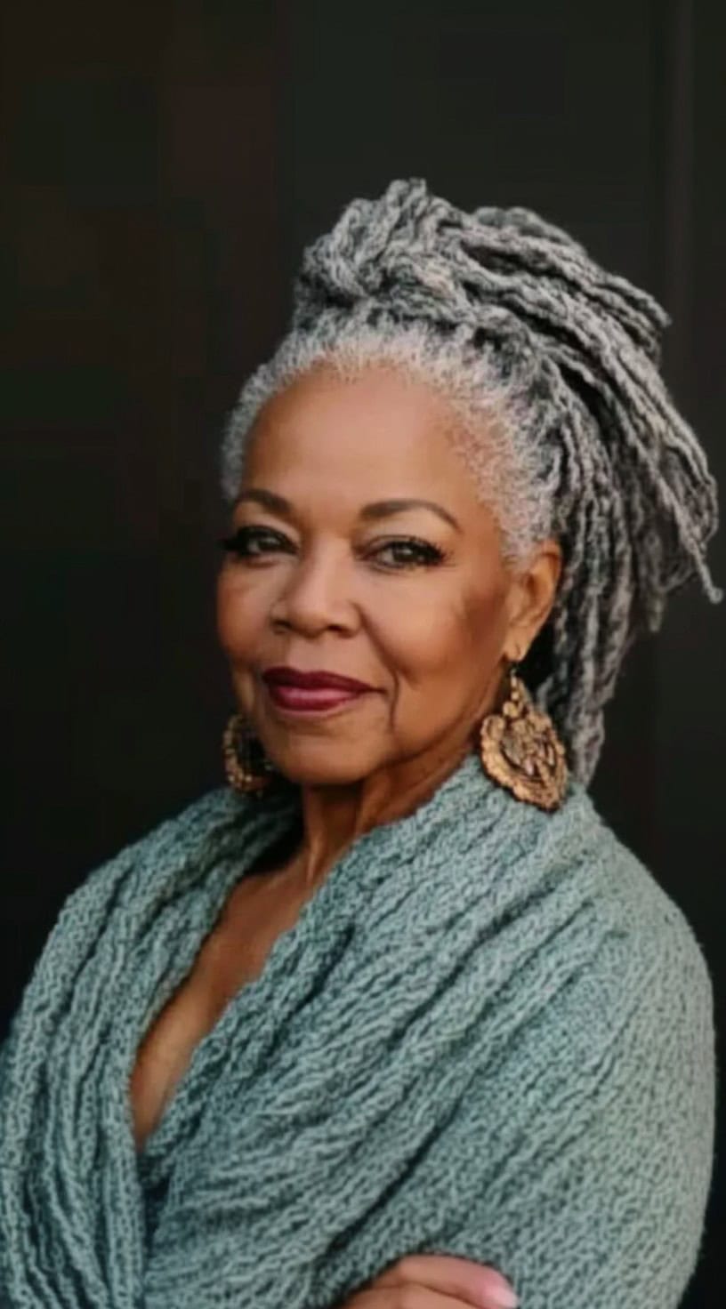 Portrait of a woman with long, thick gray locs styled into a high, elegant ponytail.