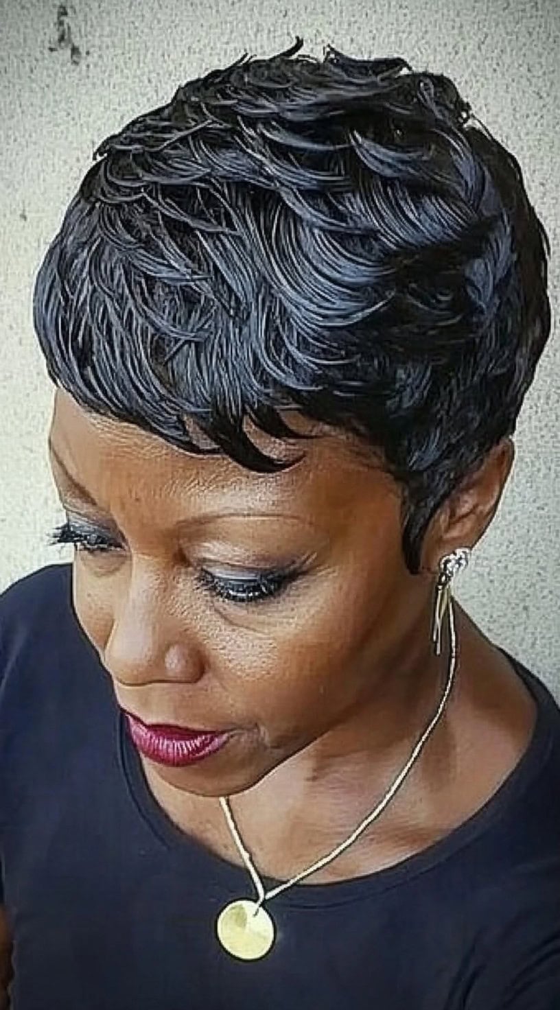 A stylish older Black woman with a short, wet-look finger waves pixie, adding a sleek and structured feel to her style.