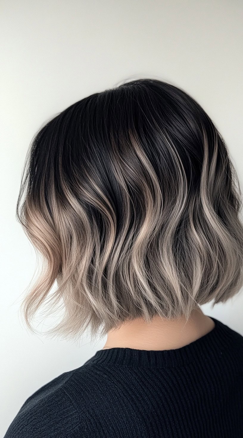 Short bob hairstyle with ash blonde balayage and dark roots.
