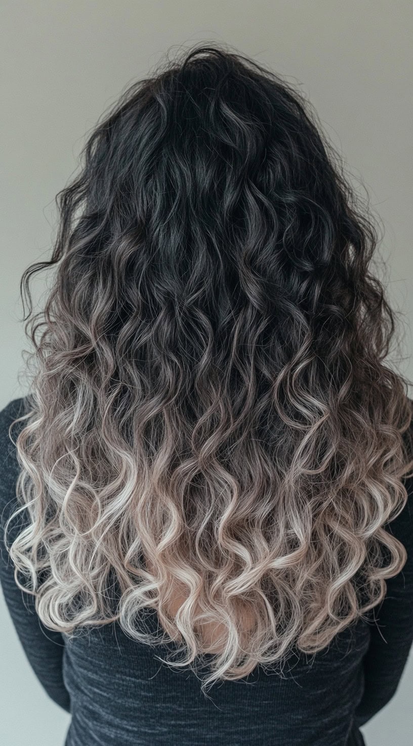 Naturally curly hair with dark roots and ash blonde balayage ends.