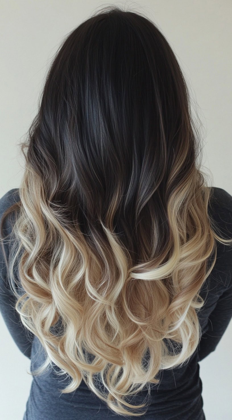 A woman with long, wavy hair in a dark chocolate to icy blonde ombre balayage.
