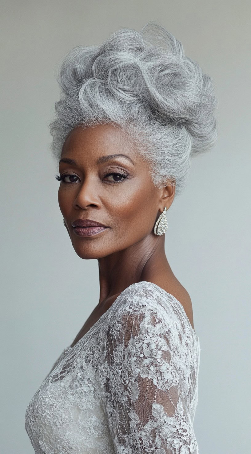 A sophisticated older Black woman with an intricate silver updo featuring soft waves and volume, wearing a lace gown and statement earrings.