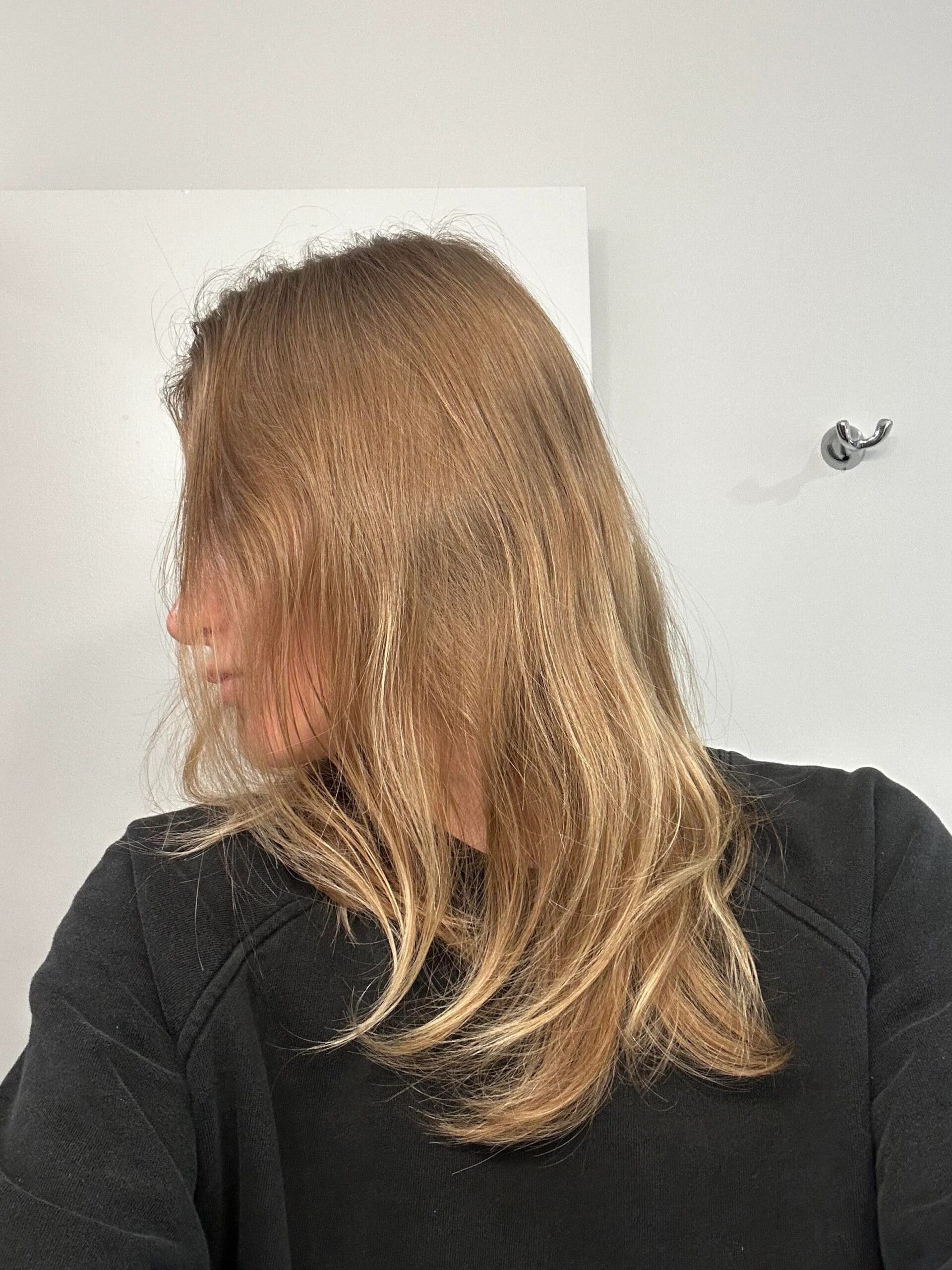 Side profile of a woman with medium-length fine blonde hair, showing the natural flatness and lack of body.