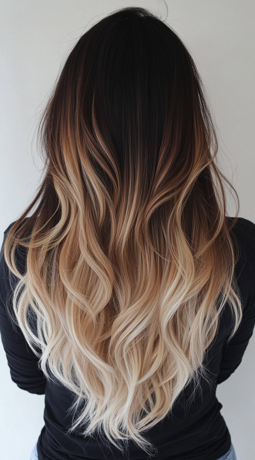 A woman with long, dark-rooted wavy hair blending into soft blonde tips.
