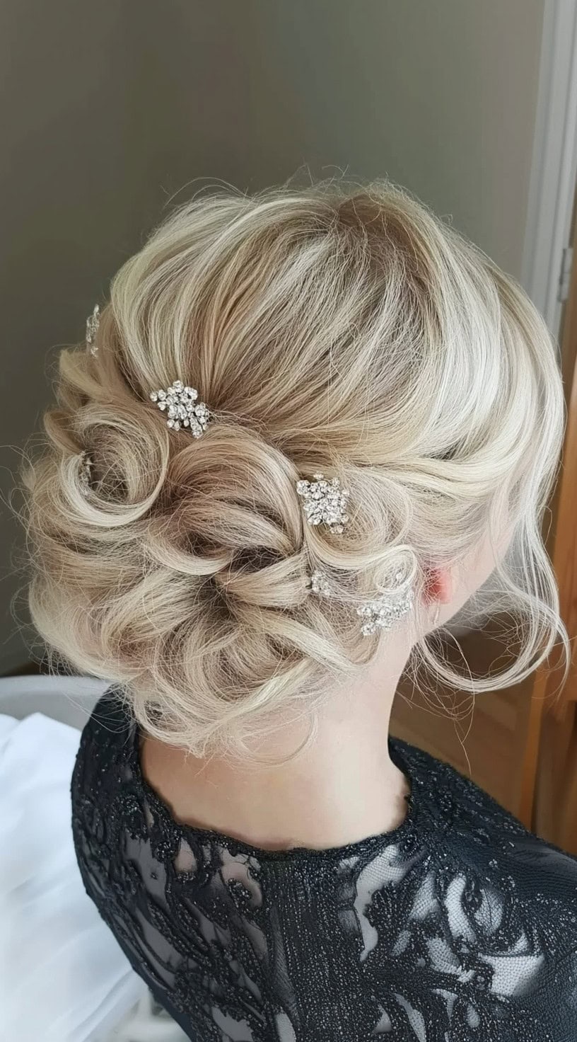 A detailed back view of a blonde updo featuring intricate curls and sparkling rhinestone hairpins for a glamorous finish.