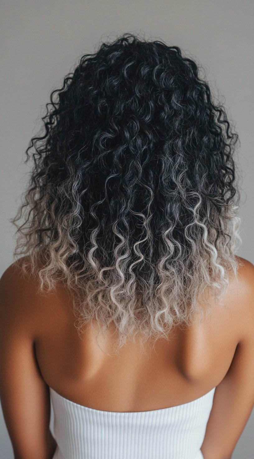 Short, curly hair with jet black roots and ash blonde ombre ends.