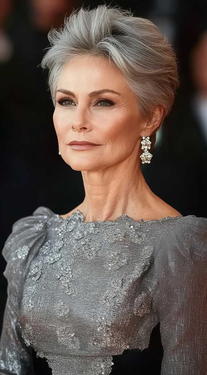 A woman with short, silver-gray hair styled in a textured pixie cut with a voluminous lifted crown.