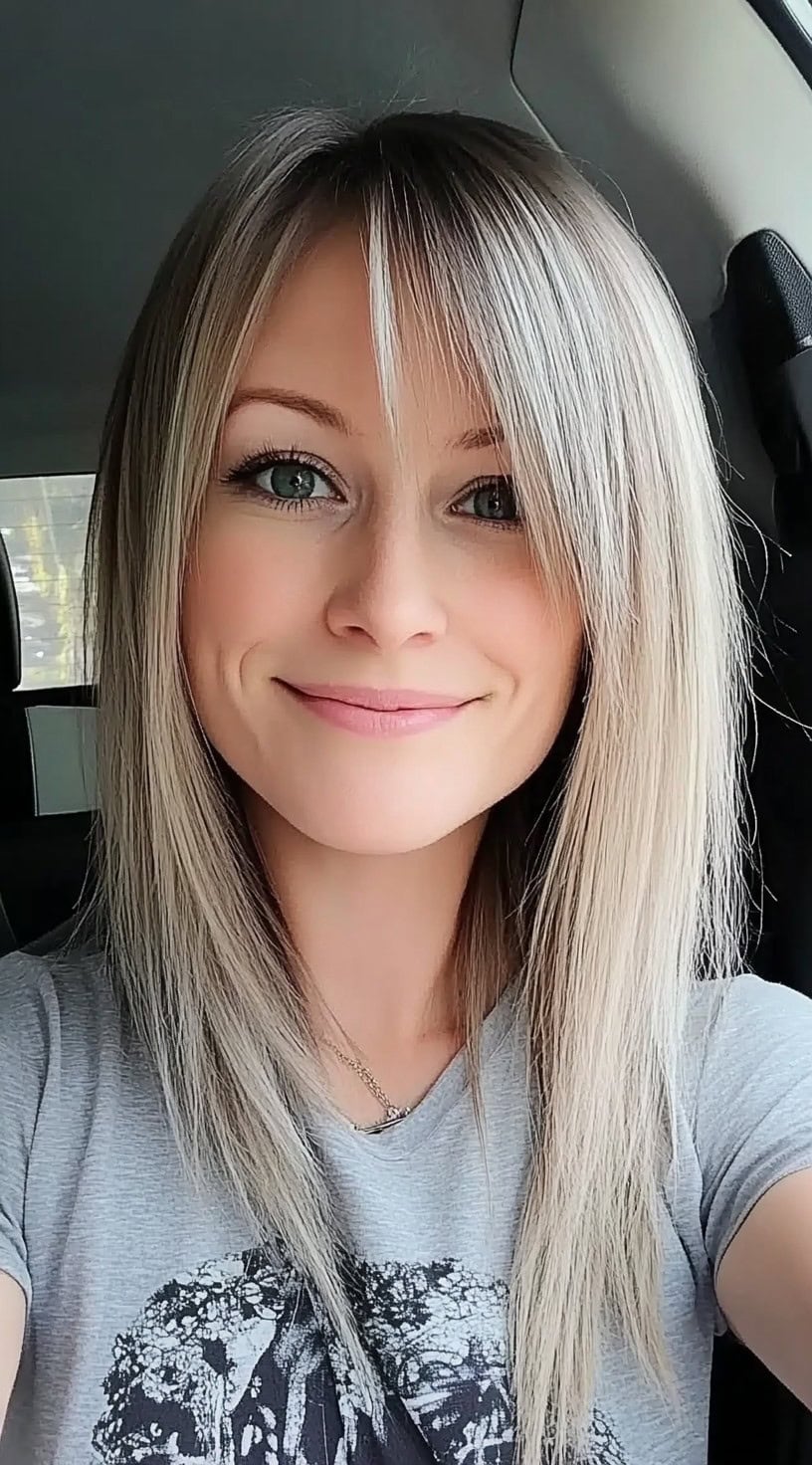 Smiling woman with long, straight ash blonde hair featuring choppy layers and a side fringe.