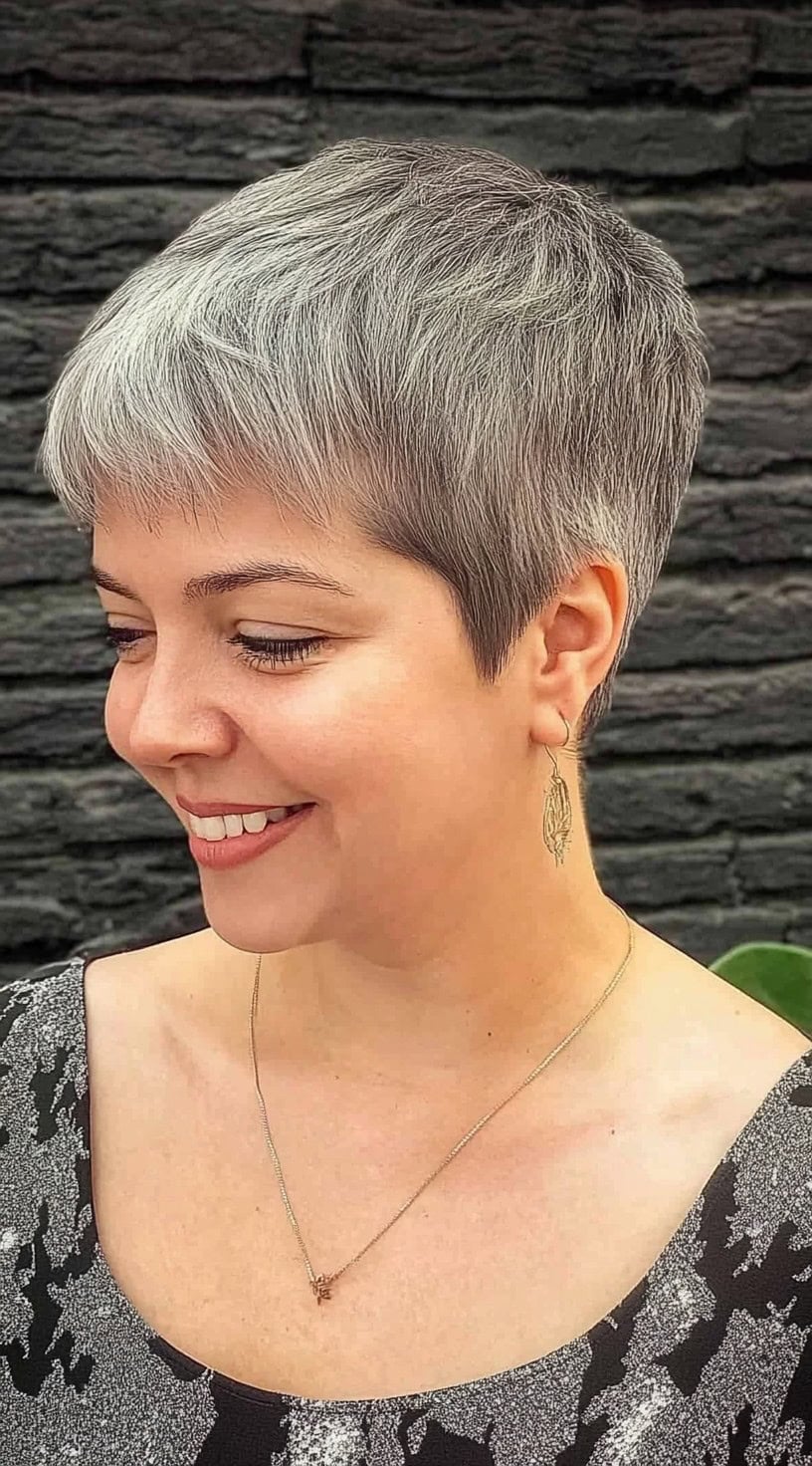 A woman with a silver-gray pixie cut and rounded edges, smiling while turned slightly to the side.